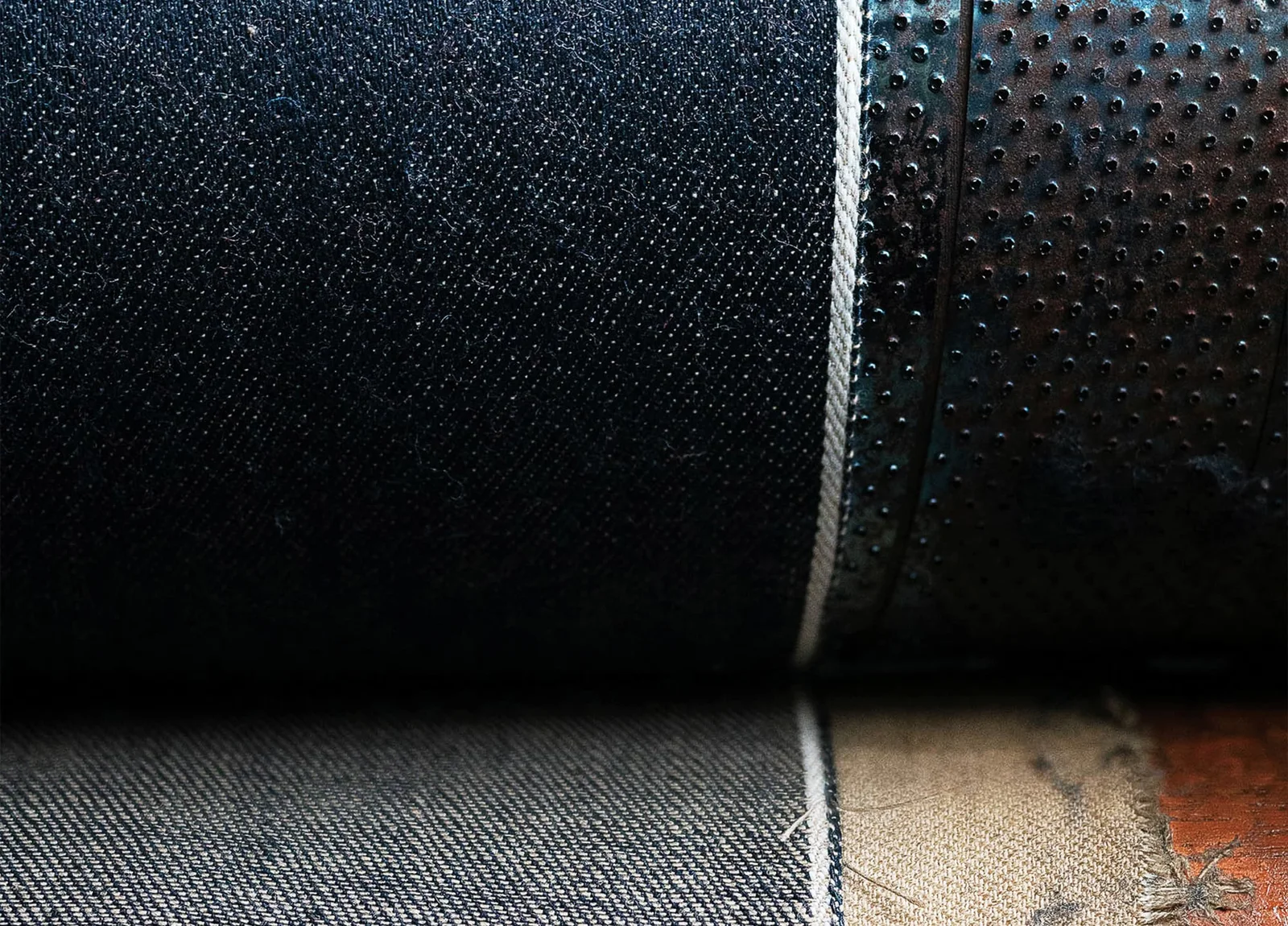 Dark denim fabric rolled on a work surface.