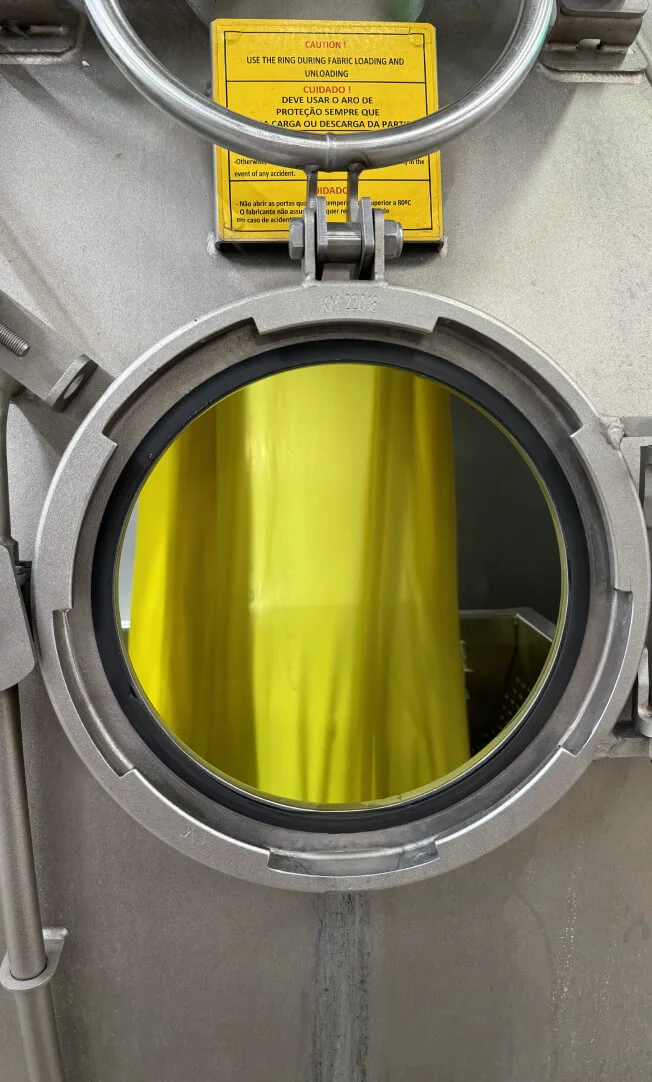 A dyeing machine with an open circular hatch.