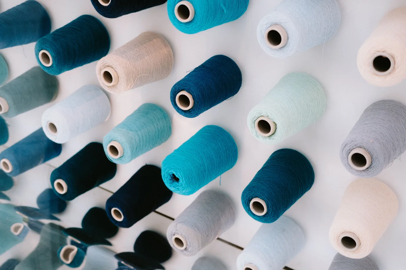 Blue, turquoise and pale yarn spools arranged together.