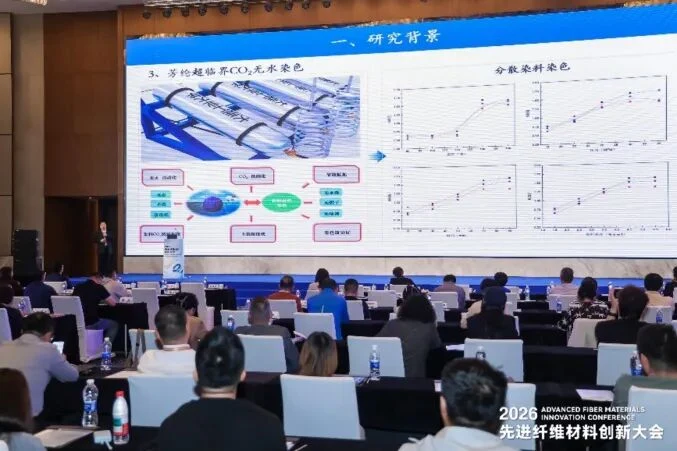 Audience and a presentation screen showing aramid supercritical CO2 dyeing at the Shengze conference.